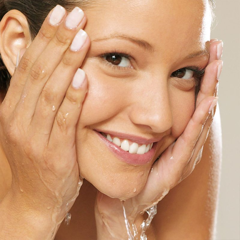A woman rinsing her face with water from the tap